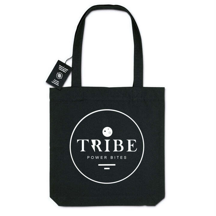 a black tote bag with Tribes logo centered on it, which is a circle with the word Tribe written big in the center, with a power bite as the dot of the eye, and then it says "power bites" small underneath the word Tribe